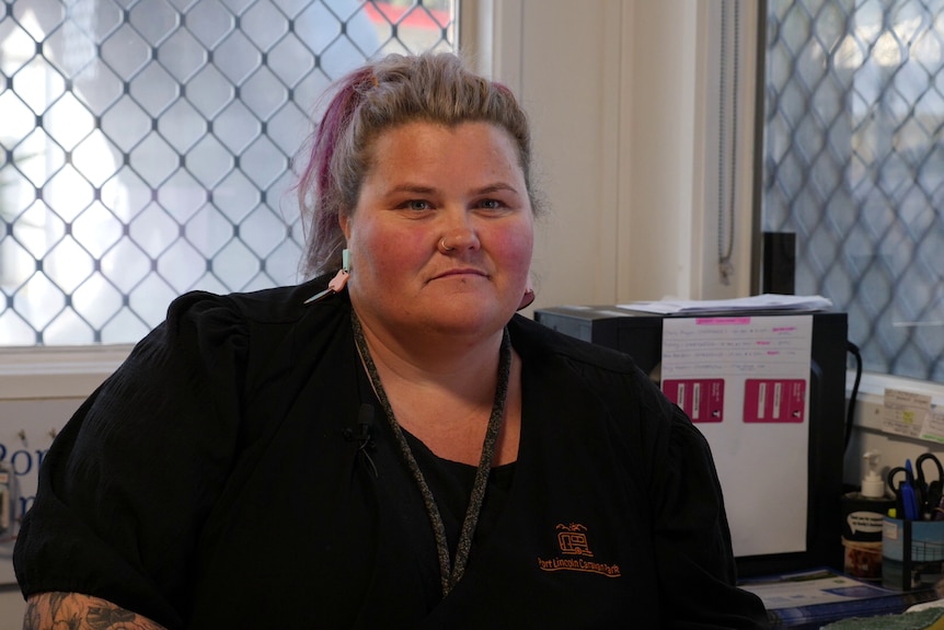 A woman sitting at a desk inside a caravan park office. 