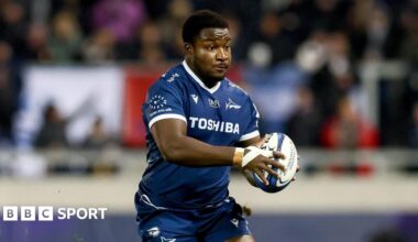 Nathan Jibulu running with the ball to his left side grasped in both hands during a match for Sale