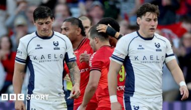 Louis Rees-Zammit (left) walks on the pitch with his head tilted down with Tom Jordan (right) walking next to him after a Toulouse try