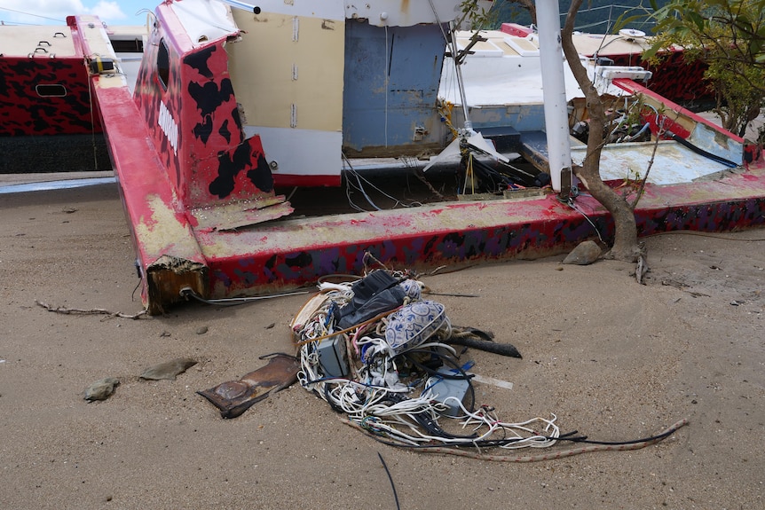 a collection of items lying next to a broken boat on a beach