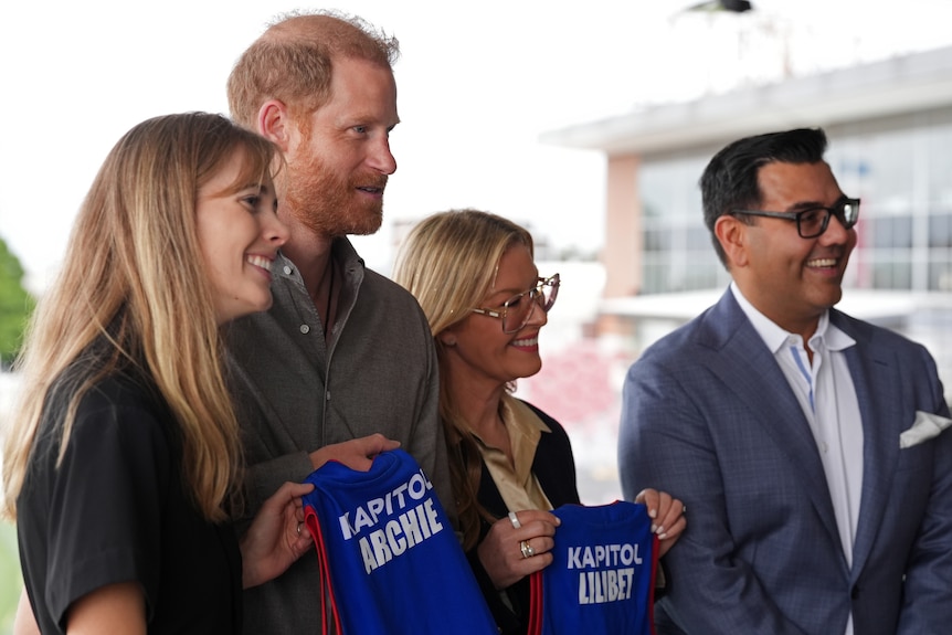 Harry holding some AFL guernseys