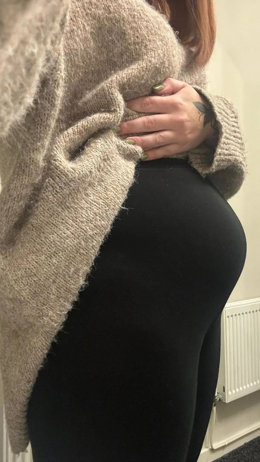 The image shows Amy holding her jumper above her tummy, to reveal a distended abdomen, caused my what she described as "endo-belly", referring to the symptoms caused by endometriosis.