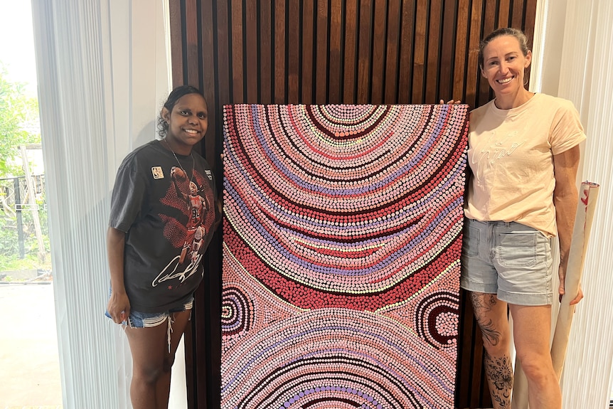 Keira Graham and Jana Pittman stand by painting.