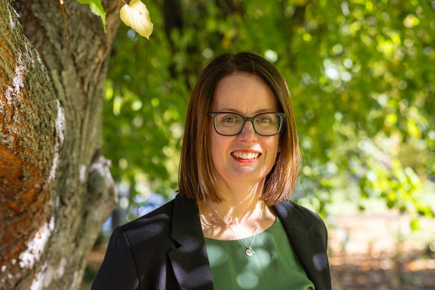 A woman wearing glasses and a dark suit.