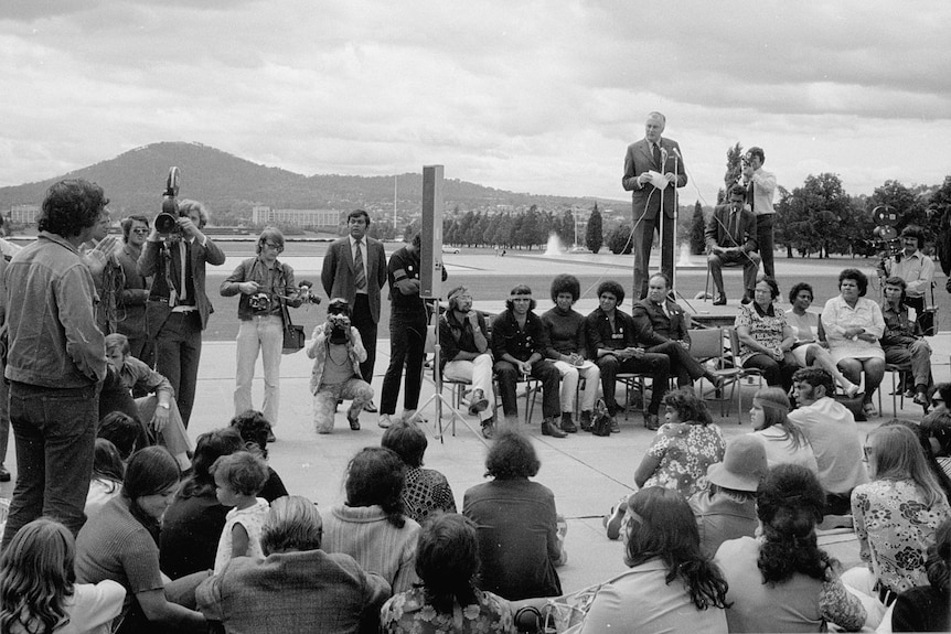 A crowd around a man on a podium. 