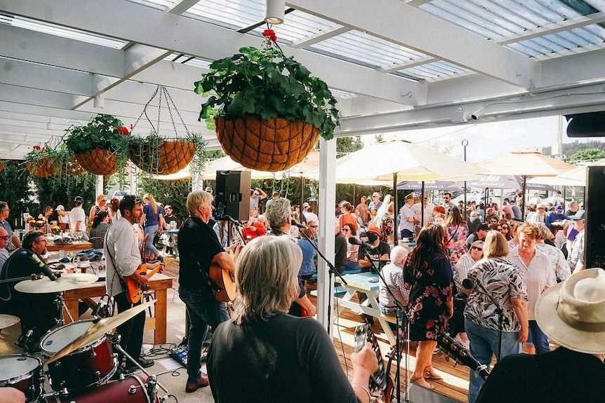 A band plays to a crowd at an outdoor venue.