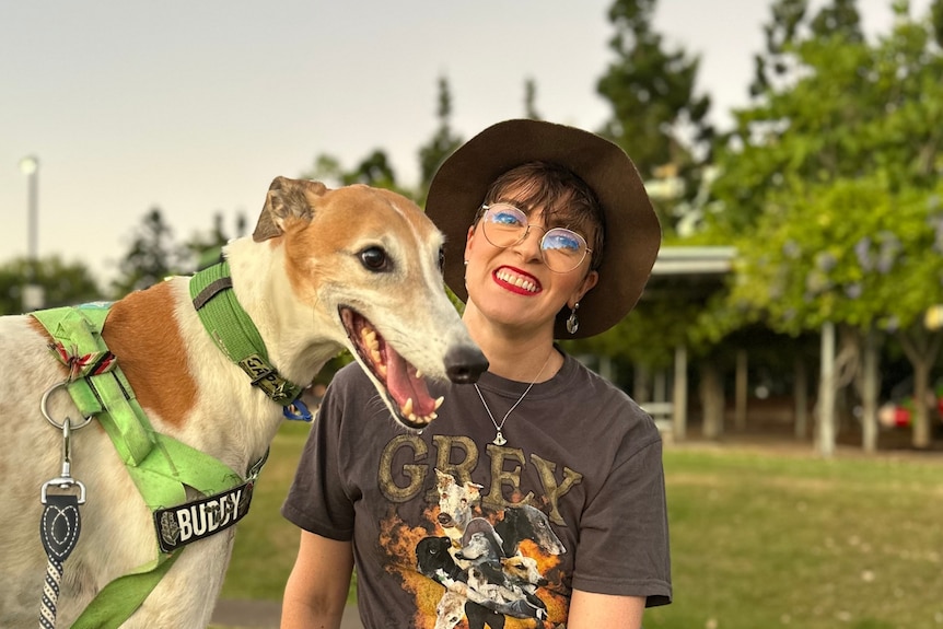 women with hat and glasses next to greyhound dog outside