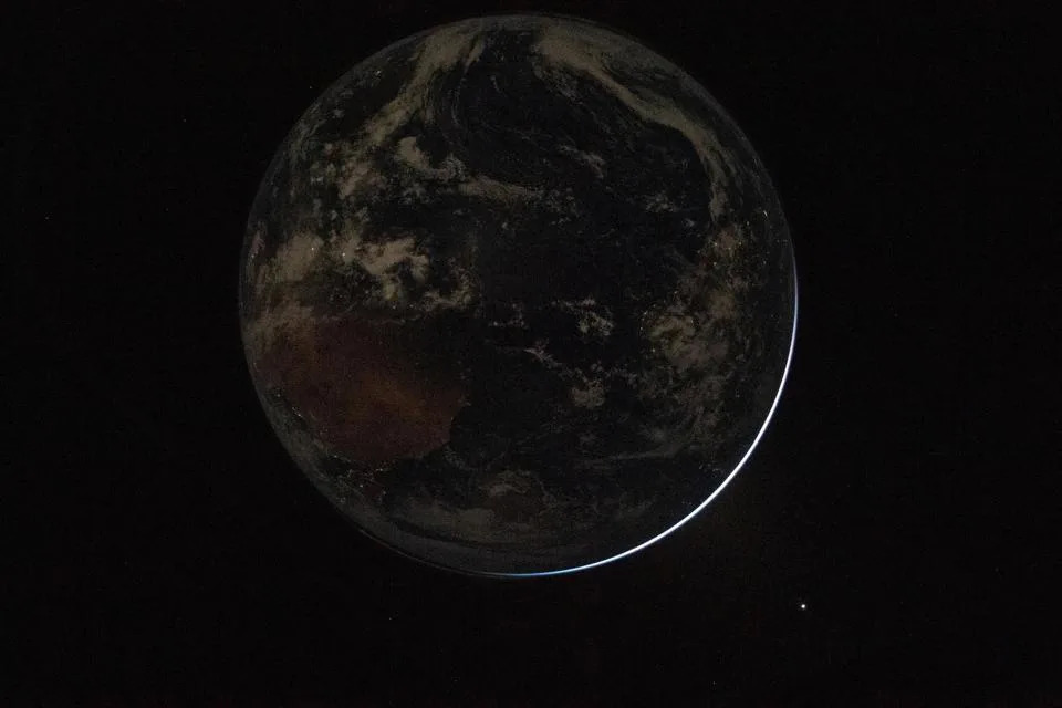 A view of a backlit Earth taken by NASA astronaut and Artemis II Commander Reid Wiseman from one of the Orion spacecraft's window after completing the translunar injection burn on April 2, 2026.