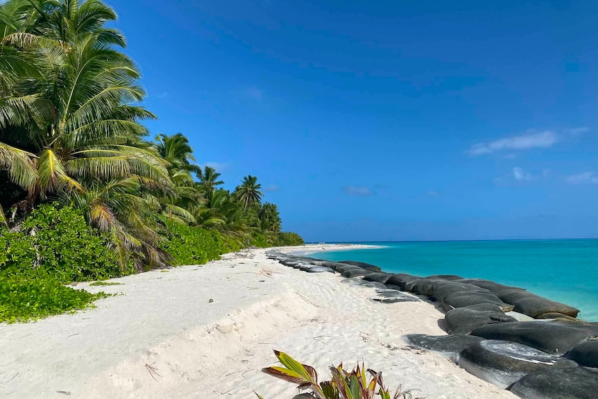 A white sandy beach lined with dark sand bags. 