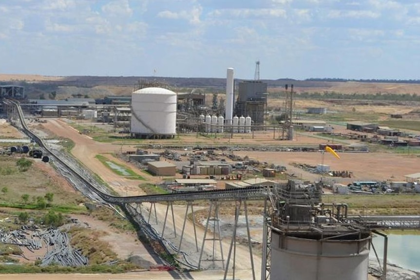 An aerial view of a mine with lots of large silos and roads, in the middle of the outback.
