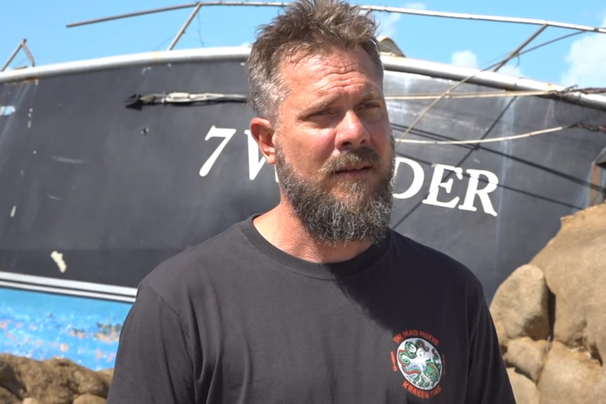 a man stands on rocks in front of a large boat