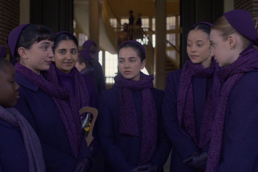 A group of young women all dressed in purple with scarfs and  headwear
