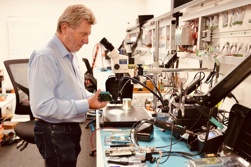 A man stands behind a microscope.