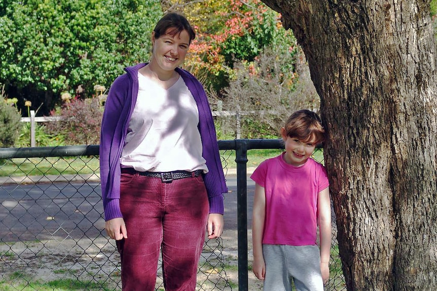 A young woman and a little girl standing under a tree