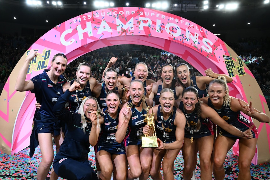 Players pose with the Super Netball trophy and their medals.