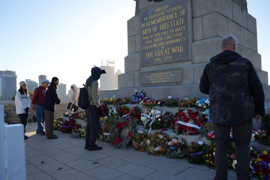 people stand at a war memorial 