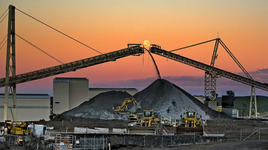 Two mine conveyors frame a full moon at sunset
