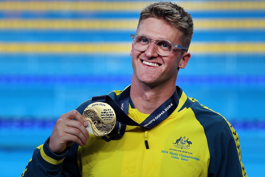 Sam Williamson smiles holding a gold medal