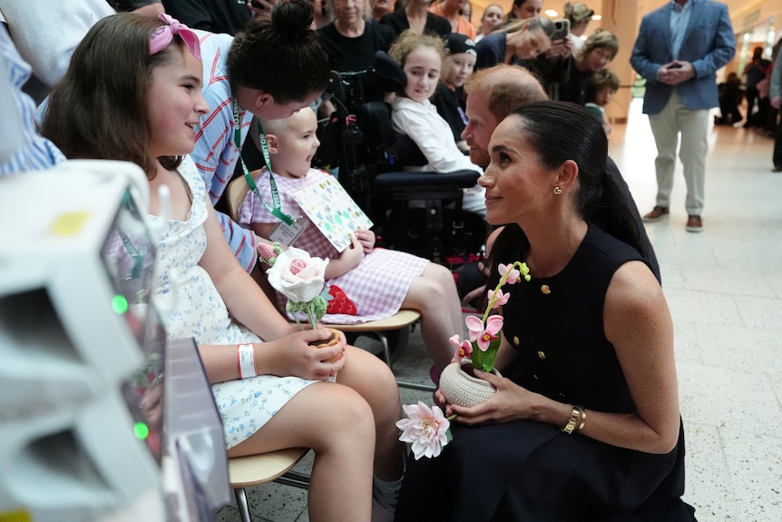 Meghan, the Duchess of Sussex, bends down while speaking with a child patient at the Royal Children's Hospital.