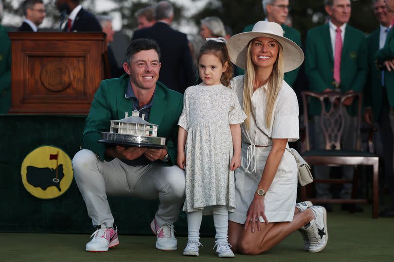 (L-R) Rory McIlroy of Northern Ireland poses with daughter Poppy and wife Erica Stoll