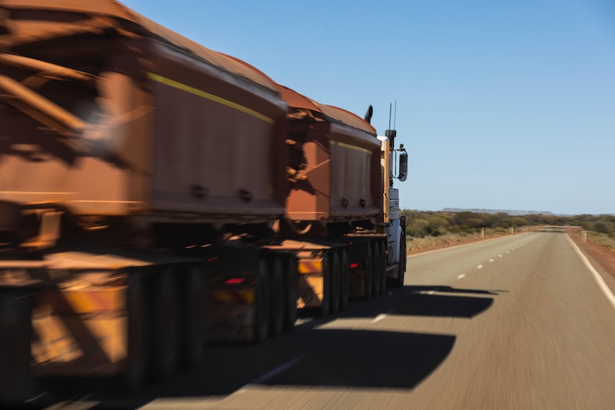 A truck on an outback highway, captured with motion blur as it drives past