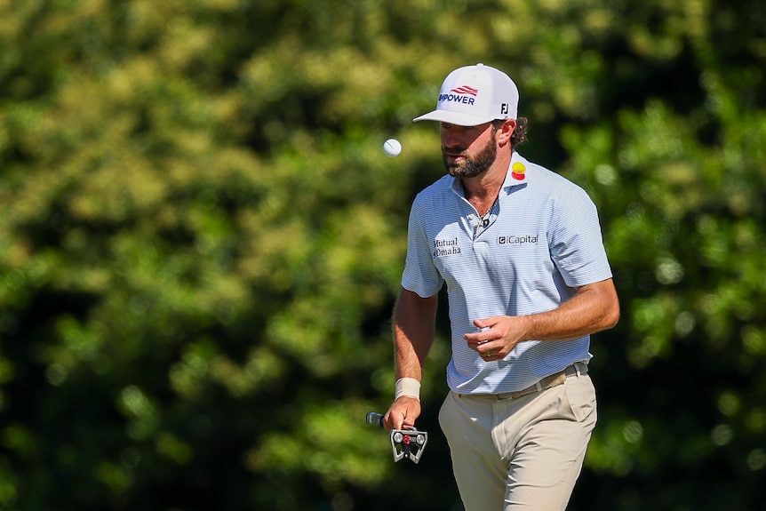 Cameron Young throws a golf ball in front of himself while walking at the Masters golfing championship.