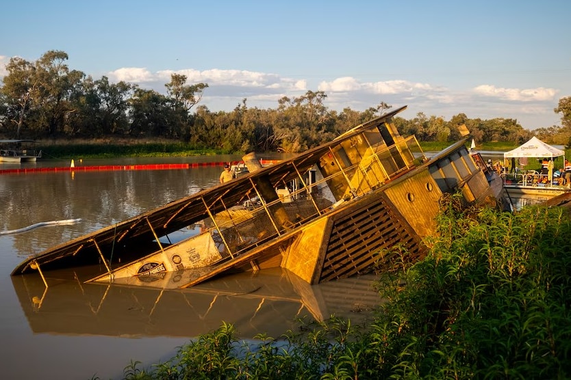 Paddle boat half submerged in a murky river.