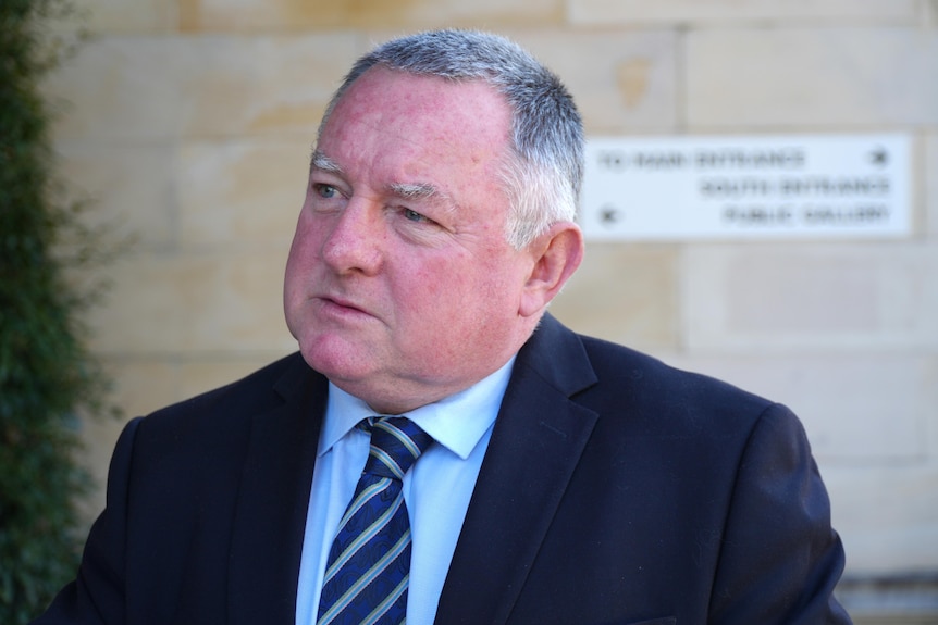 Steve Thomas wears a suit, looking to left of frame.