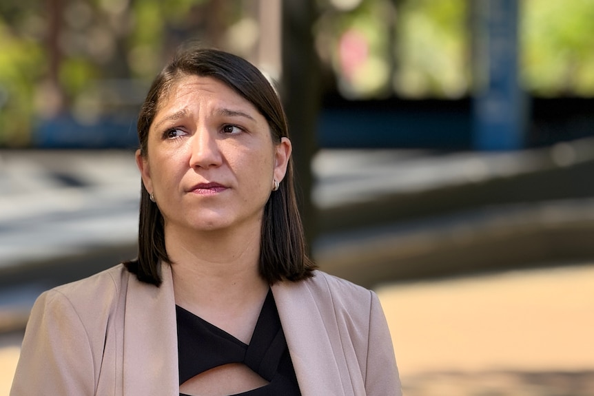 A woman looking concerned talks a a person in a blue top slightly out of camera
