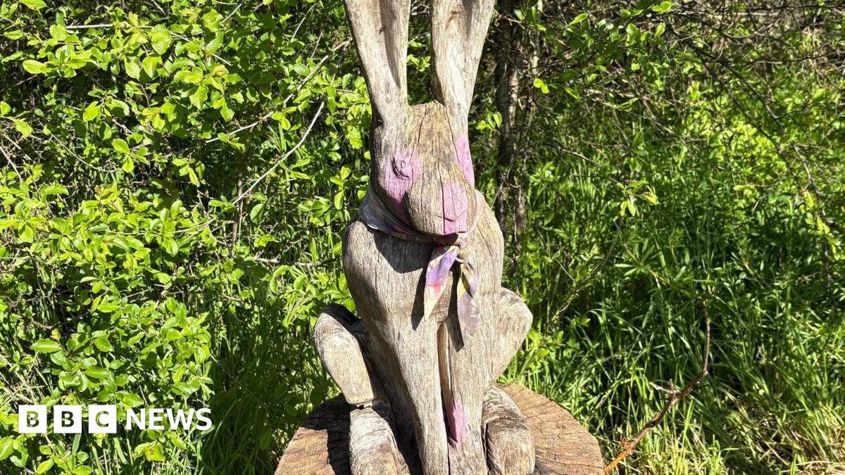 A wooden hare with pink paint splashed on its eyes, nose and paws.