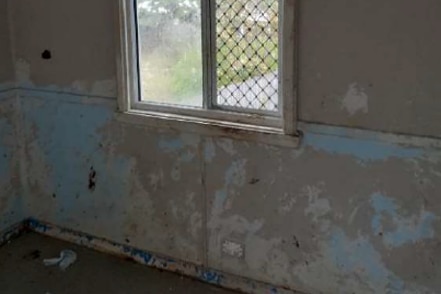 a window in a house looking out positioned on a dirty and damaged wall