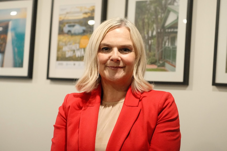 A close-up shot of a young blonde woman in a red blazer.