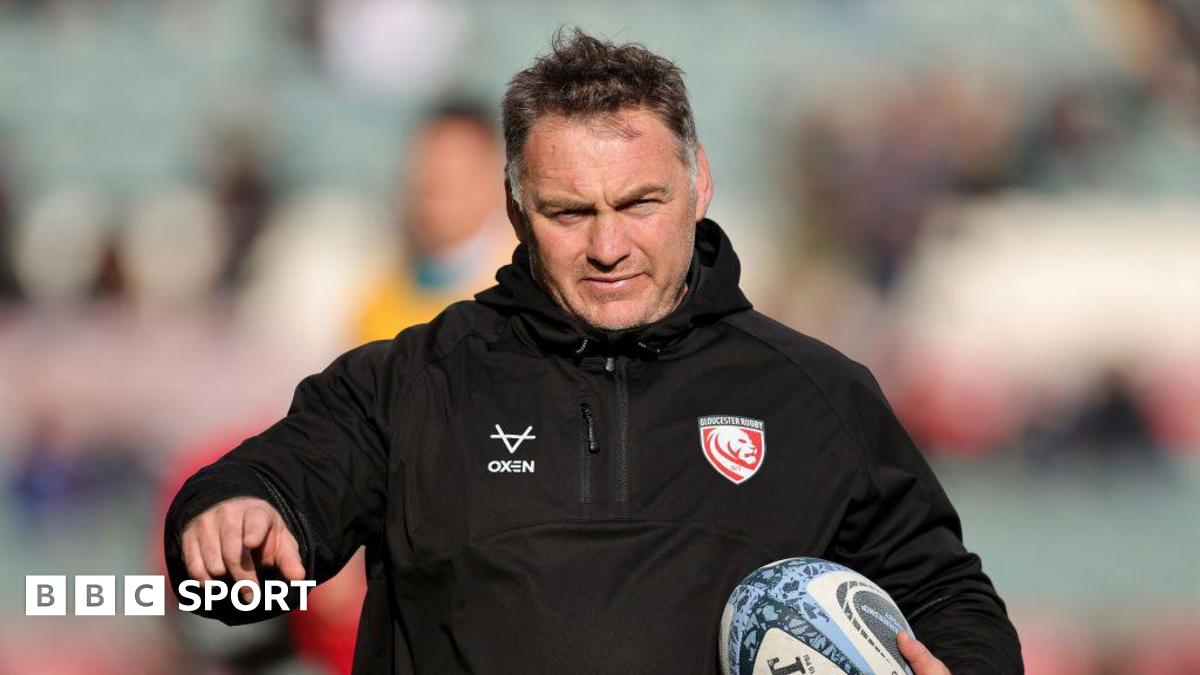 Trevor Woodman holds a rugby ball under his left arm to his chest while holding his right arm out and pointing his index finger during a pre-game warm-up