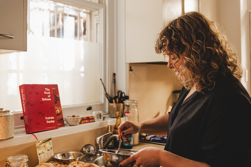 Gemma Plunkett preparing a meal in her light-filled apartment kitchen.