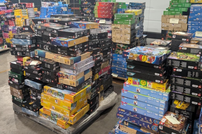 Several boxes of Lego on pallets in a large shed