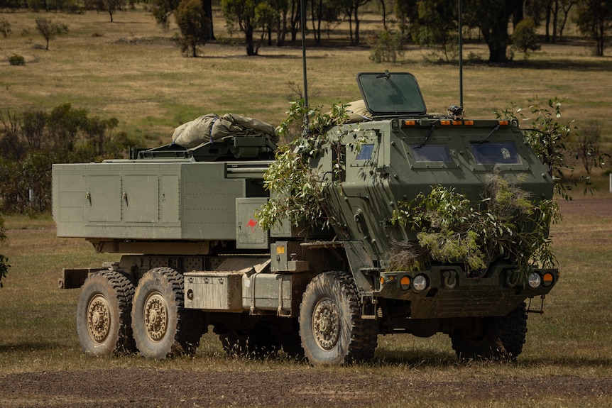 a military truck with a missile system mounted on the back drives across a landscape