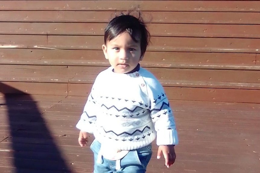 A young boy standing in front of brown steps
