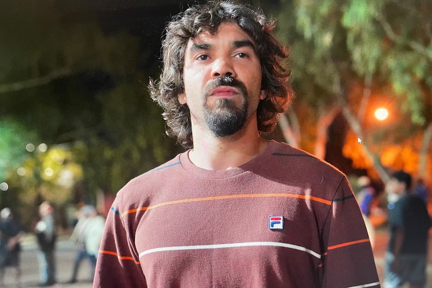 A man with a tshirt stands in front of a group of people.