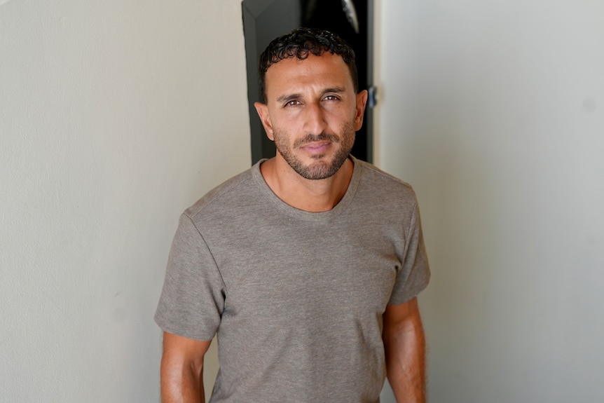 Shabbo wears a dark shirt and has a serious expression.