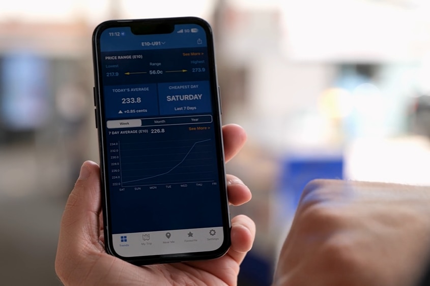 A person holding a mobile phone with the fuel check app open.