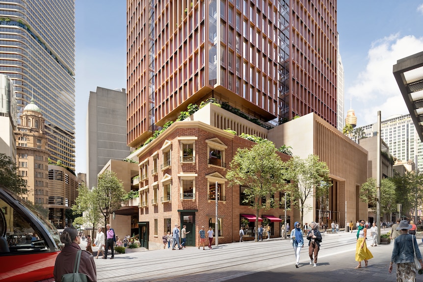 A number of metro lines running past a red brick building through a busy street.