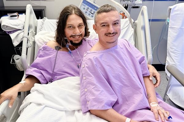 Sajarn sits on Codey's hospital bed after his kidney transplant surgery. Both are smiling