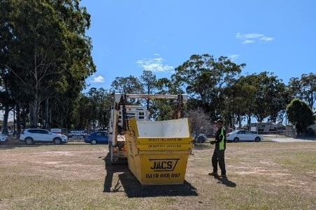 A truck unloading a large yellow skip bin.