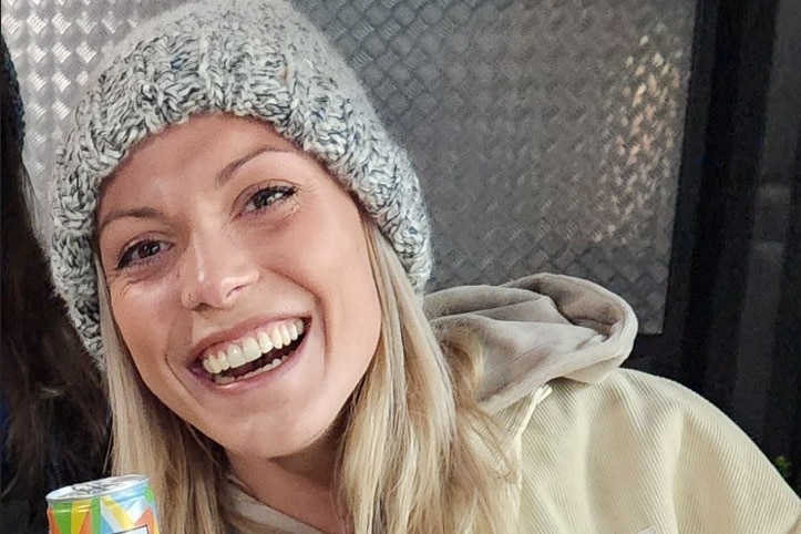 Celine Cremer, 31-year-old woman smiling big wearing a grey beanie and jacket