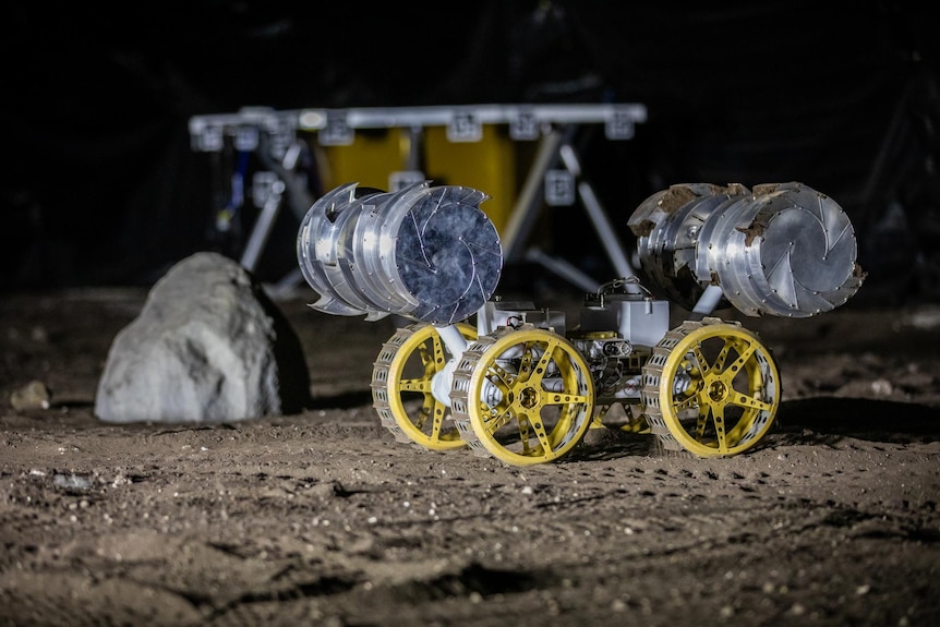 A rover with bladed wheels for excavation on a dusty, Moon-like surface.