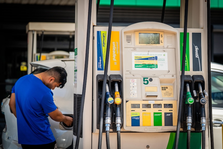 A man in a blue t-shirt at a petrol pump