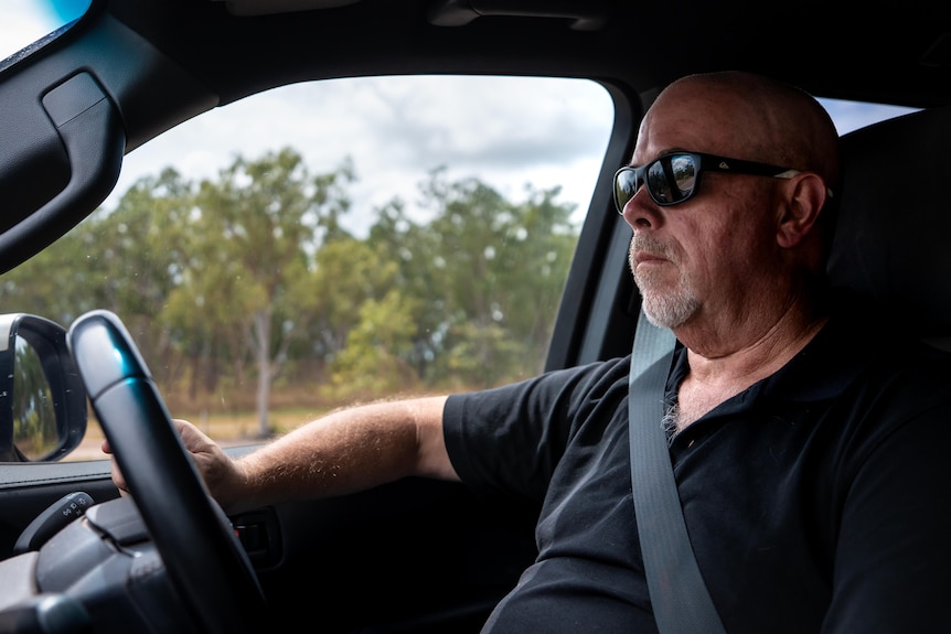 A man in sunglasses driving a car.