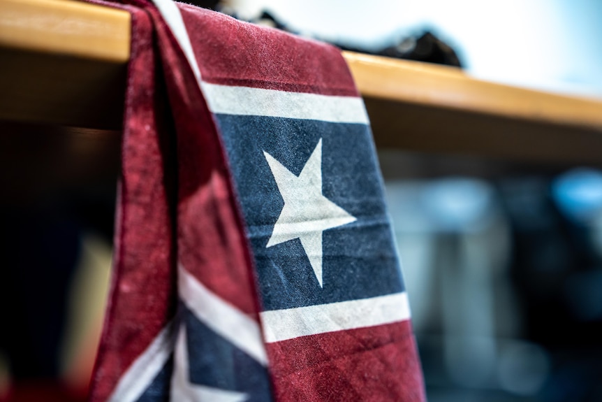 A flag hanging off a table that's blue white and red.