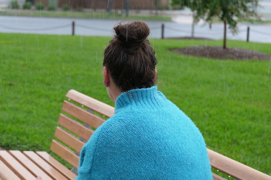A woman sitting on a bench looking away from the camera