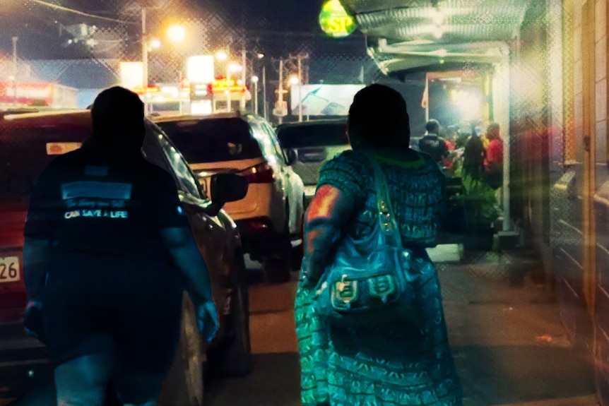 Two woman walk down the footpath of a city past cars